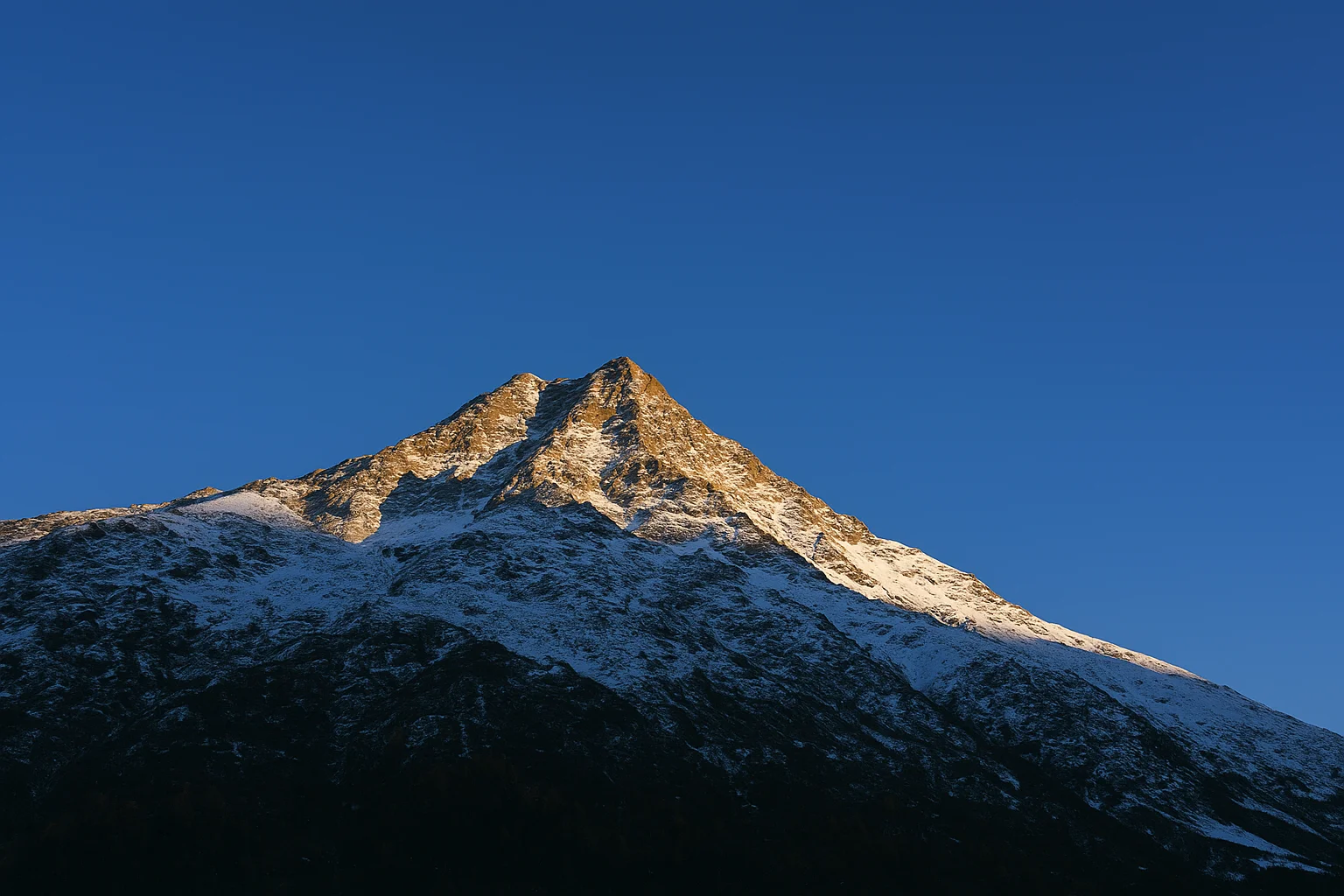 Pico coberto de neve brilhando com a luz dourada do pôr do sol.