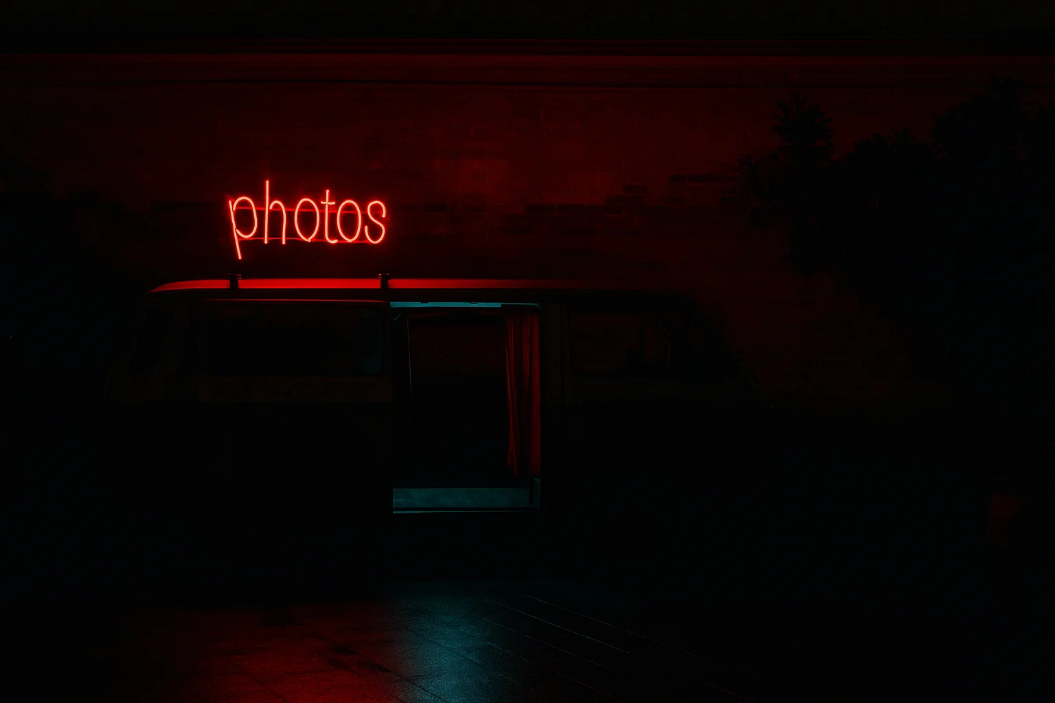 vintage photo van with a red neon “photos” sign at night