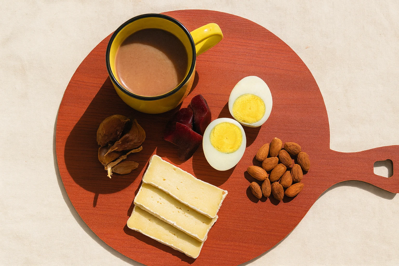 Сыр, яйца, миндаль и тёплый напиток на деревянной доске