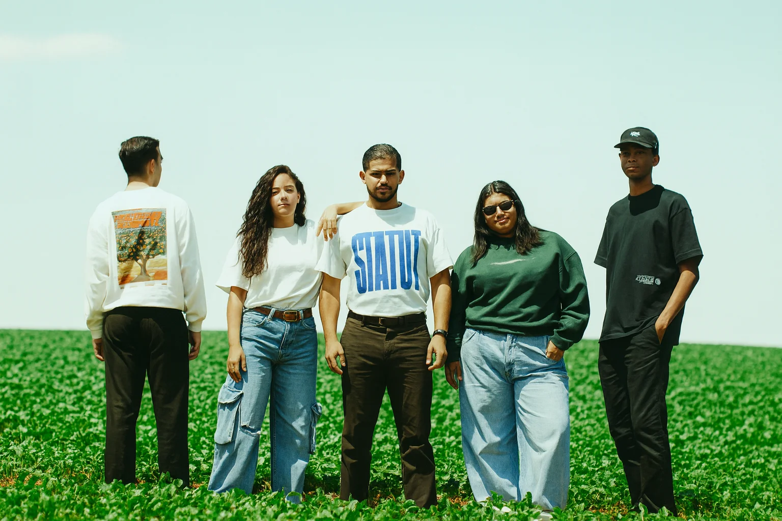 Năm bạn trẻ tạo dáng cùng nhau trên cánh đồng rộng với trang phục hiện đại