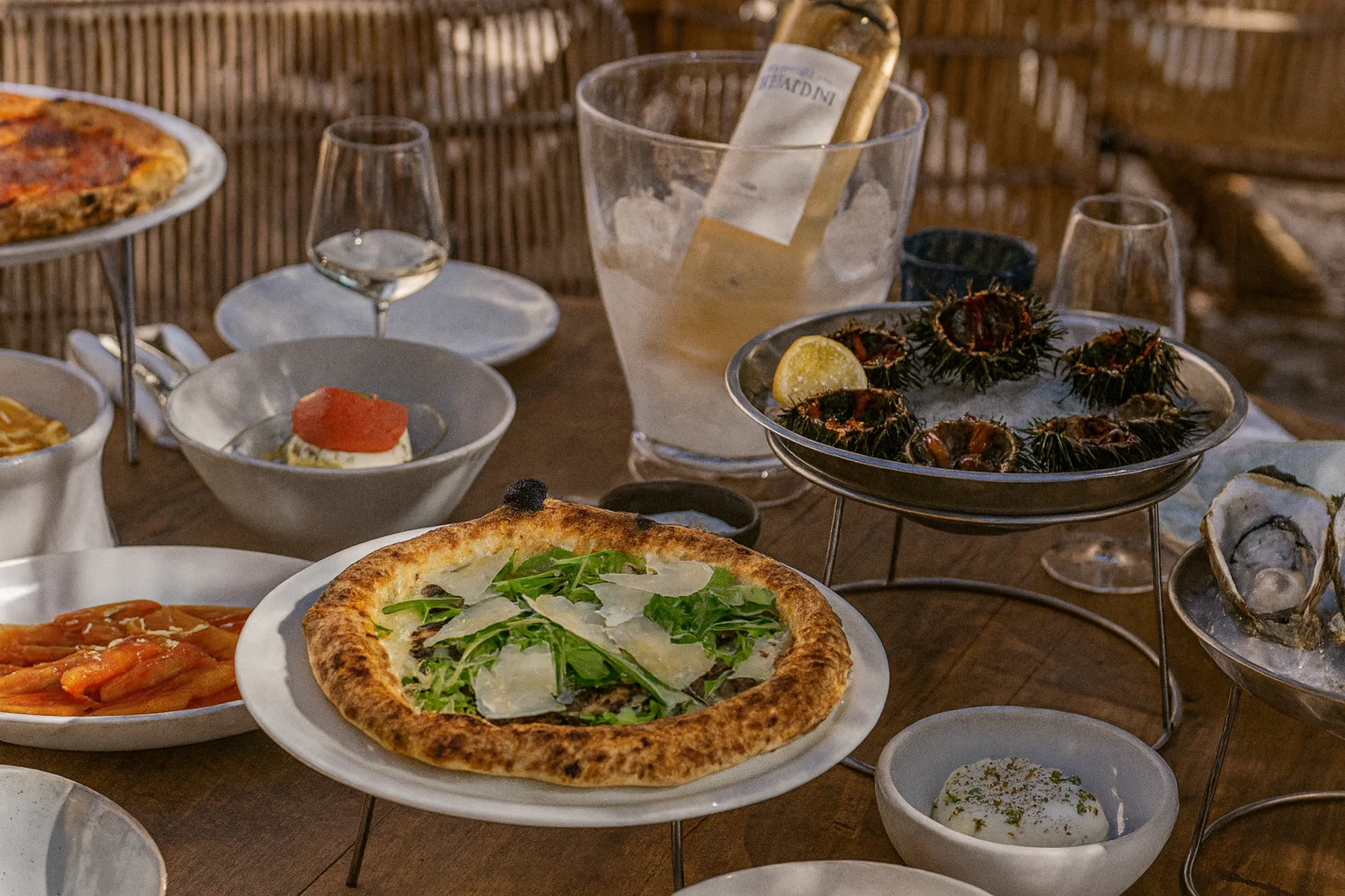 Bàn ăn gourmet với pizza, hải sản và rượu vang lạnh