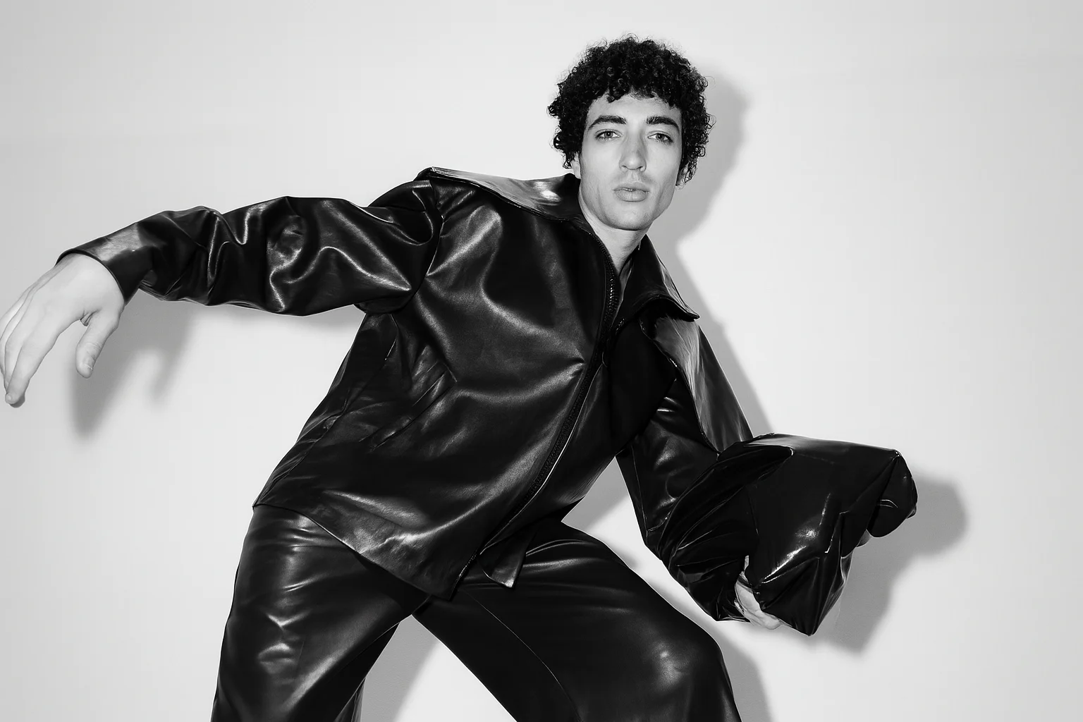 Foto horizontal em preto e branco de um modelo com roupa moderna de couro preto.