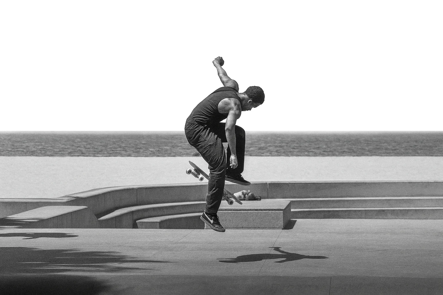 sahilde zıplama hareketi yapan skateboard sporcusunun siyah beyaz fotoğrafı